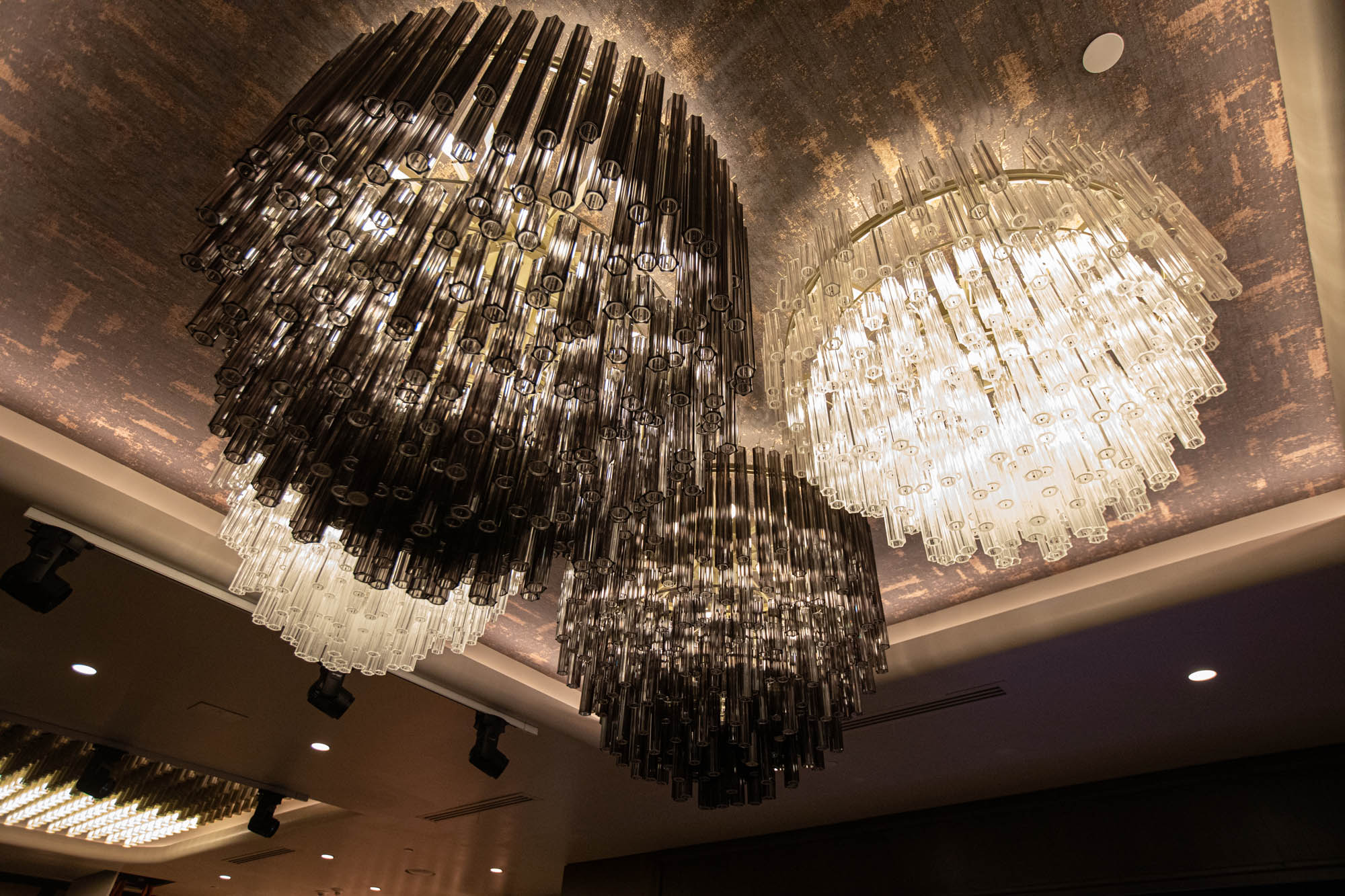 Glass chandeliers against an art deco, stylish ceiling.